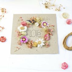 a card with the word love written in it surrounded by dried flowers and wooden scissors