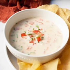 a white bowl filled with dip surrounded by tortilla chips