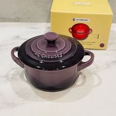 a red and black pot sitting on top of a counter next to a box with the lid open