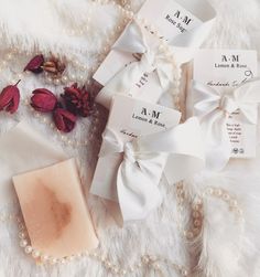 some soaps and flowers are laying on a white furnishing with pearls around them