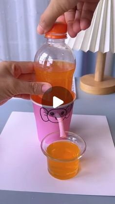 someone is pouring orange juice into a pink cup