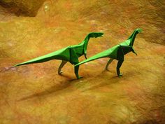 two origami dinosaurs are standing on the ground