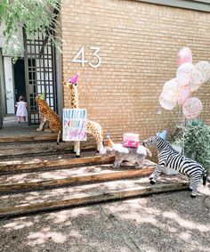 some zebras and giraffes are standing on the steps in front of a building