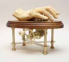 a wooden sculpture of a hand on top of a spinning wheel