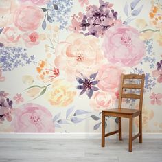 a wooden chair sitting in front of a wall with flowers painted on the wall behind it