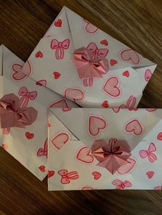 two envelopes with hearts and bows on them are sitting on a table next to each other