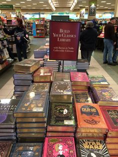 many books are stacked on top of each other in a store aisle with people looking at them