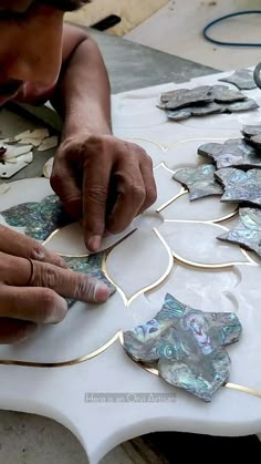 a man working on some kind of art project with glass and metal pieces in the shape of flowers