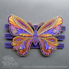 a purple and orange butterfly hair clip on a gray surface with the words, livemaster