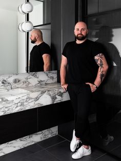 a man standing in front of a bathroom mirror with his hands on his hips while looking at himself in the mirror