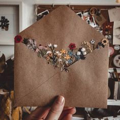 a person holding up a piece of paper with flowers on it