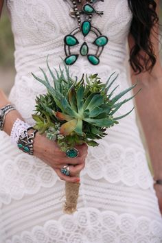 a woman in a white dress holding a succulent bouquet