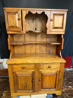 an old wooden hutch sitting on top of a piece of plywood flooring