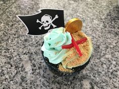 a cupcake with green frosting and a pirate flag on the side sitting on a table