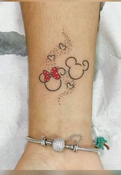 a wrist tattoo with mickey and minnie mouse heads on it's side, in the shape of hearts