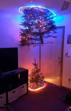 a christmas tree in the corner of a room with lights on it and a tv