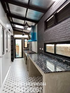 a kitchen with black and white tile flooring and counter tops, along with an open door leading to another room