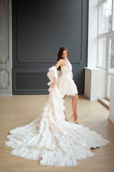 a woman in a white dress is posing for a photo with feathers on the floor