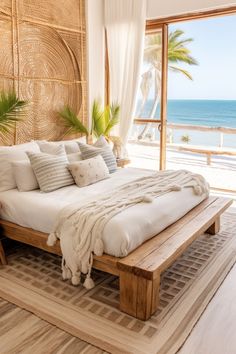 a large bed sitting in the middle of a bedroom next to a window with an ocean view