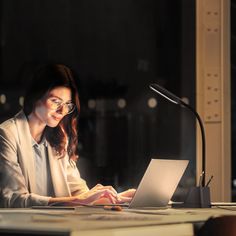 a woman sitting at a desk with a laptop computer in front of her and a microphone to the side