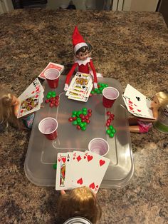 an elf sitting at a table with cards and candy