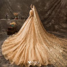 a woman in a gold wedding dress with a veil on her head and flowers around her neck