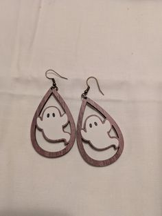 a pair of wooden earrings with ghost cutouts on the front and back of them