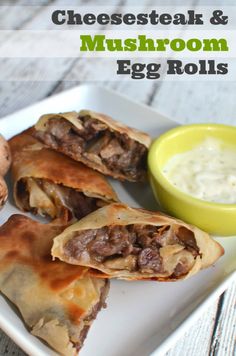 cheesesteak and mushroom egg rolls on a white plate with a bowl of ranch dressing