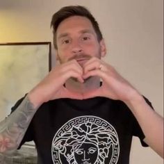 a man with tattoos on his arms making a heart shape while standing in front of a mirror