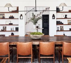 a dining room table with chairs and a bowl of fruit on it in front of bookshelves