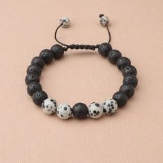 This handmade wax cord bracelet features Dalmatian Jasper and lava stones. Dalmation Jasper is a stone of action, calming the overactive mind while also promoting motivation and enthusiasm. It is known to encourage a child-like joy and energy, as well as reflection and self-examination. Lava Beads are made from Natural Volcanic Basalt. The lava stones acts as a sponge-like carrier as it soaks up your oils and retains them in the core of the Bead. Adjustable 8mm Lava Stone Beaded Bracelets, Adjustable Black Lava Stone Bracelet, Casual Black Friendship Bracelets With 8mm Beads, Casual Everyday Lava Stone Beaded Bracelets, Casual Lava Stone Beaded Bracelets As Gift, Casual Lava Stone Beaded Bracelets For Everyday, Casual Braided Bracelets With 8mm Beads As Gift, Casual Braided Bracelets With 8mm Beads For Gifts, Casual Braided Bracelets With Natural Stones For Healing