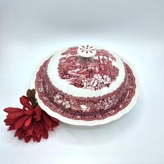 a red and white plate with a flower on the side, sitting next to it