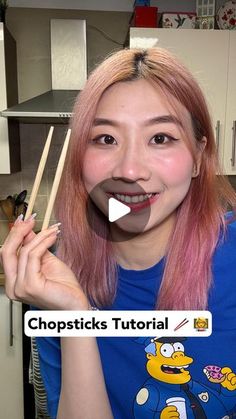 a woman with pink hair holding chopsticks in front of her face and smiling