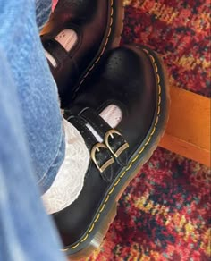 a person wearing black shoes and jeans standing on a carpeted floor with their feet in the air