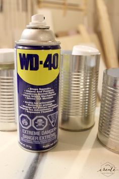 a can of wd - 40 next to two cans of other tins on a table