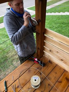 a man working on an outdoor project with wires attached to the side of a fence