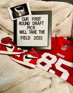 a pair of sneakers and a jersey are laying on a bed next to a sign that reads, our first round draft will take the field