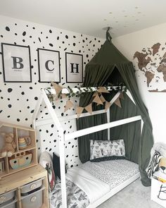 a child's bedroom with black and white polka dot wallpaper, green canopy bed frame