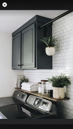 a black and white laundry room with lots of plants on the shelf next to the washer