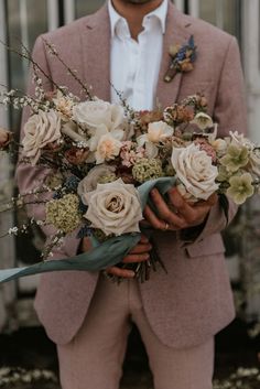 a man in a suit holding a bouquet of flowers