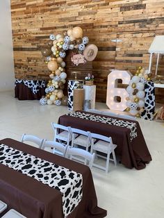 two tables covered in brown and white tablecloths at a cow themed birthday party