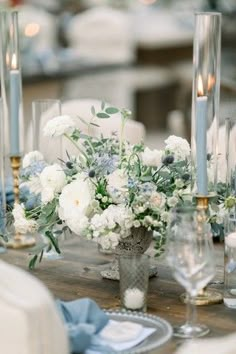 an arrangement of flowers and candles on a table