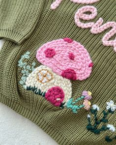 a green sweater with pink and white flowers on it