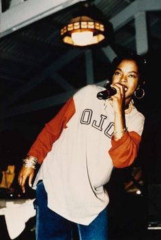 a woman singing into a microphone while standing in front of a table