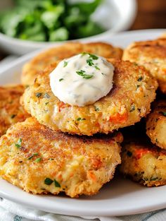 some crab cakes on a white plate with sour cream