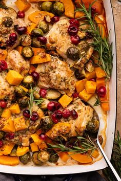 a white casserole dish filled with chicken, vegetables and cranberry sauce