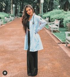 a woman is standing in the middle of a walkway wearing a blue coat and black pants