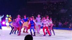 a group of people standing on top of an ice skating rink in front of a crowd