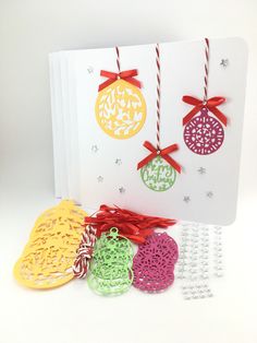 an open card with paper ornaments hanging from it's sides and string attached to the cards