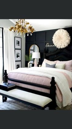 a black and white bedroom with pink bedding, chandelier, mirror and bench